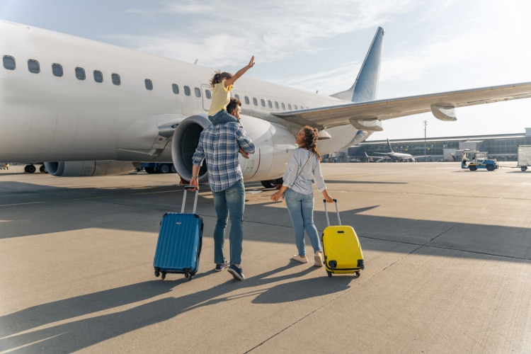 a family stands outside of a plane with their suitcases